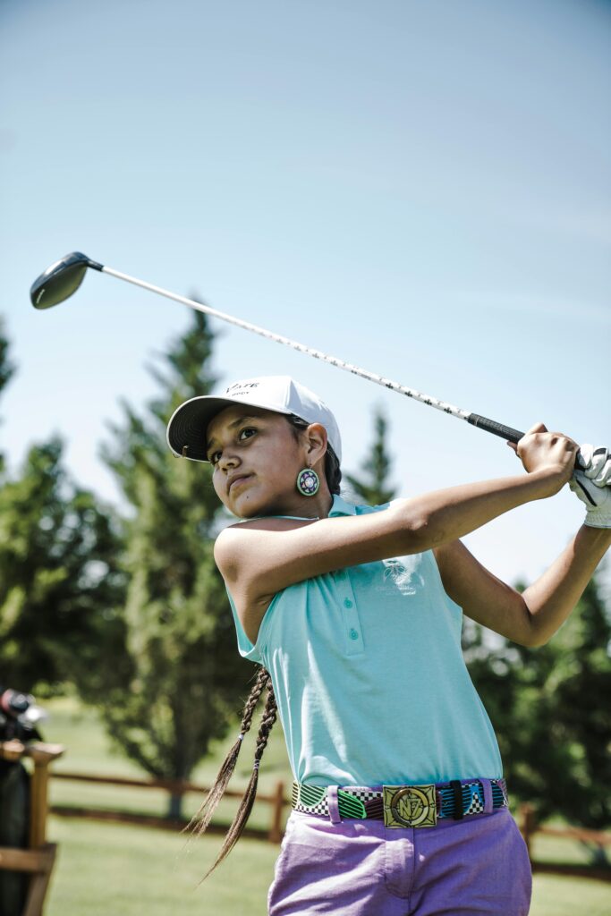 A young female golfer enjoying a sunny day on the golf course with focus and style.